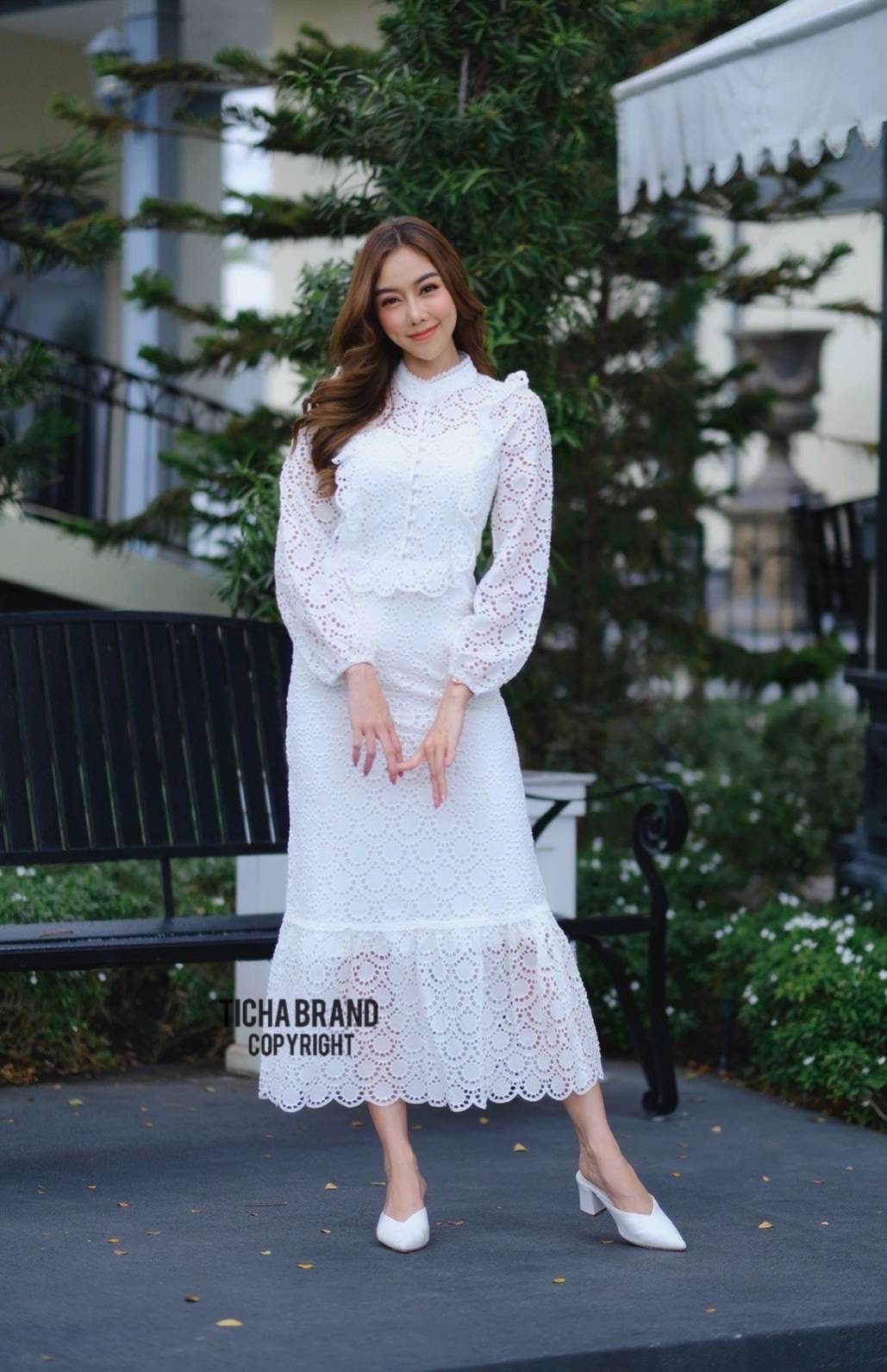 เดรสผ้าคอตตอนปักลายฉลุตัวยาว ทรงคอสูง แขนยาว ช่วงกลางอกแต่งกระดุมยาวลงมาถึงช่วงเอวเข้ารูป
